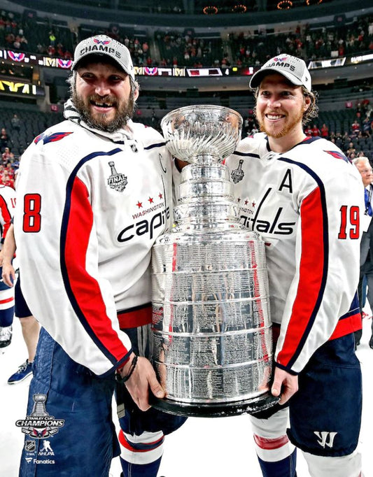 Two hockey players holding the Stanley Cup in a stadium setting