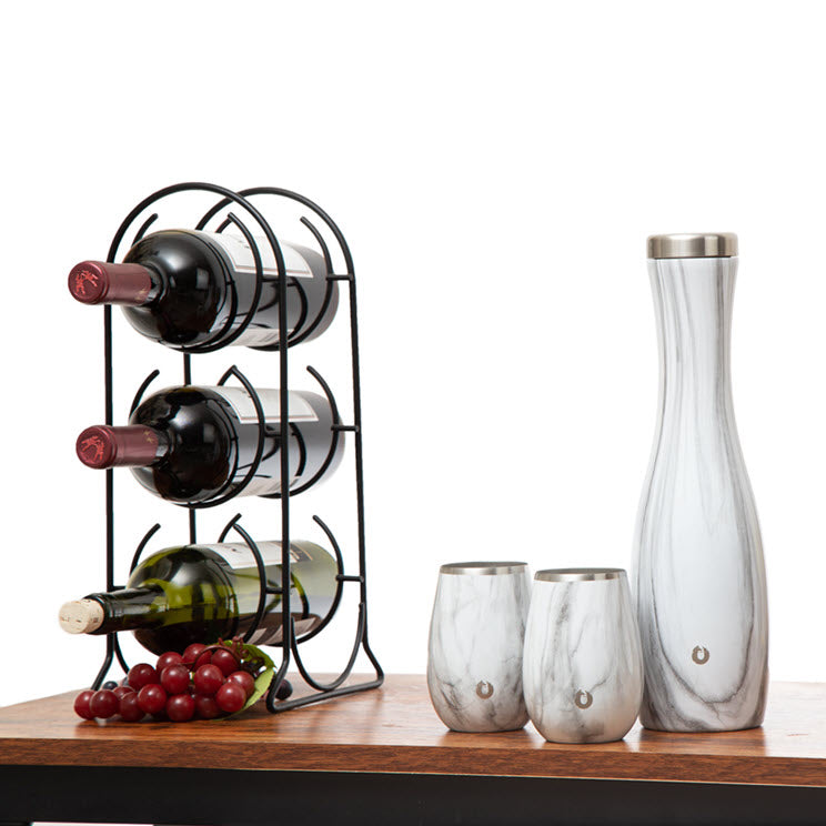 Wine rack with bottles, grapes, and carafe on a wooden surface with a white background
