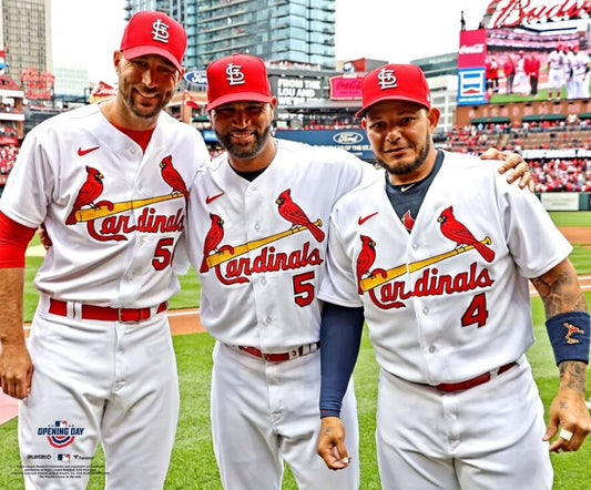 Three baseball players in St. Louis Cardinals uniforms on a field.