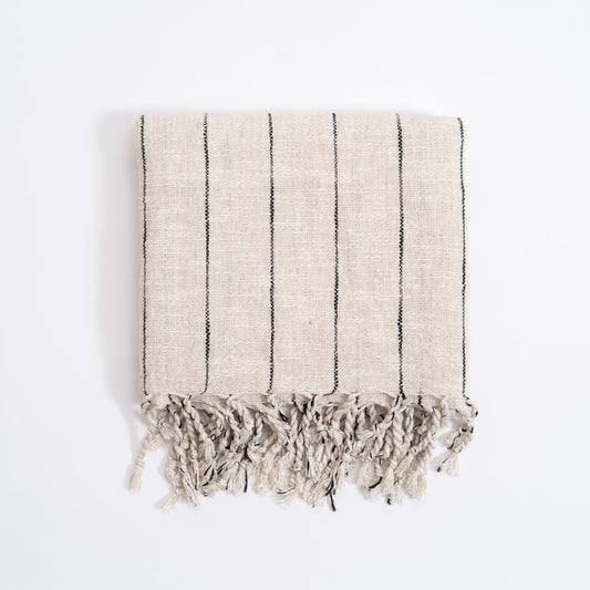 A striped Turkish hand towel in beige and gray, with fringed edges, displayed on a white background.