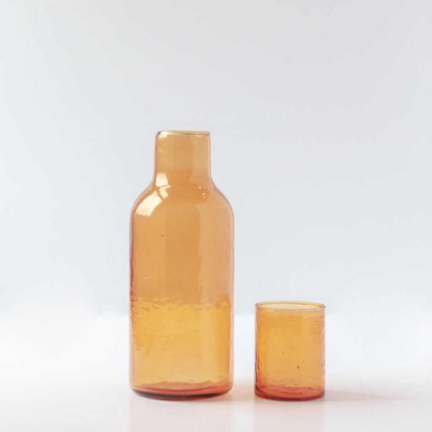 A set of two amber-colored glass carafes, one large and one small, with a textured surface and a matching lid.