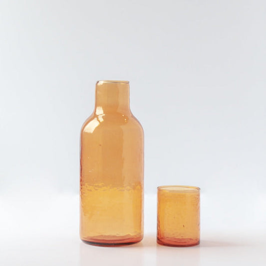 A set of two amber-colored glass carafes, one large and one small, with a textured surface and a matching lid.