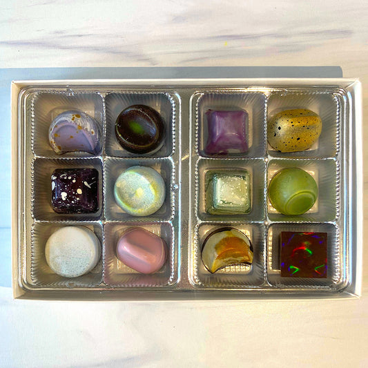 Assorted colorful marbles in a clear plastic container on a light background